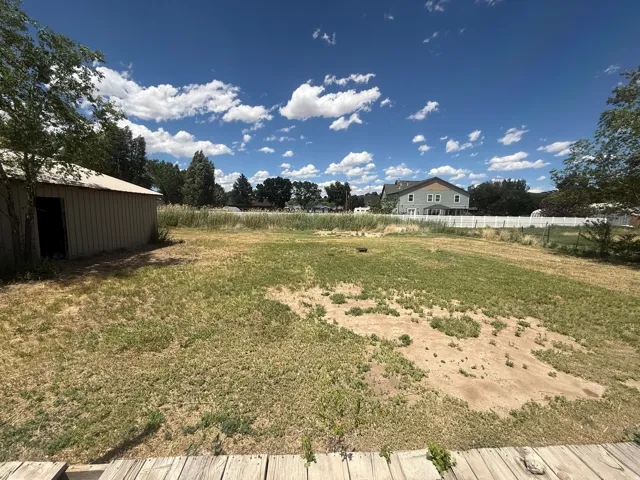 Expansive outdoor space featuring a detached storage shed, natural landscaping, and a partial wood deck
