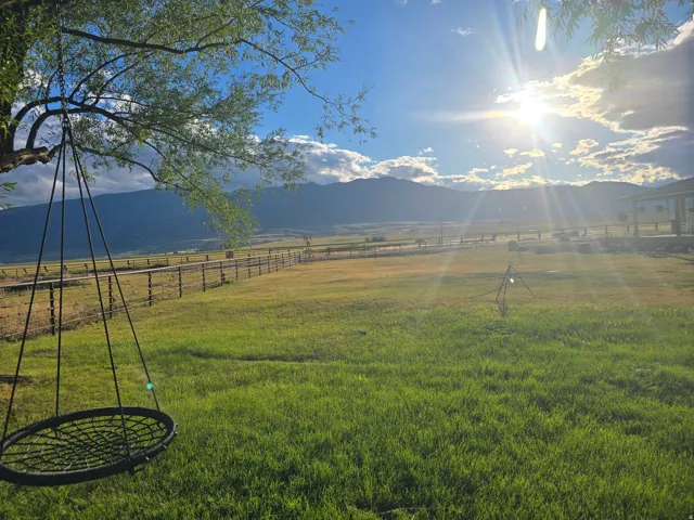 Expansive green space featuring a large lawn area, distant mountain scenery, and a tree with a hanging swing
