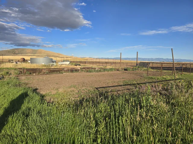 Fenced open land with distant mountains and rolling hills