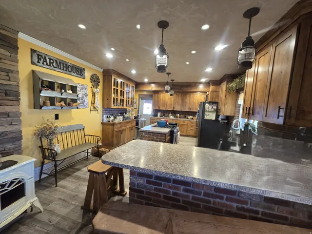Spacious kitchen featuring extensive wood cabinetry, an island with a built-in cooktop, and a breakfast bar with brick detailing