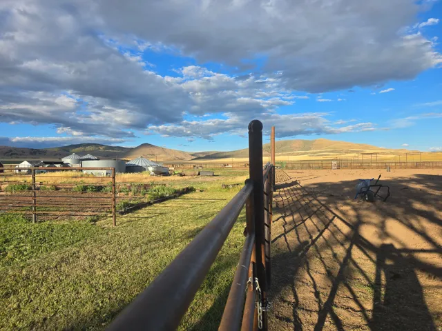 Expansive fenced outdoor area featuring a dirt surface and distant mountain scenery