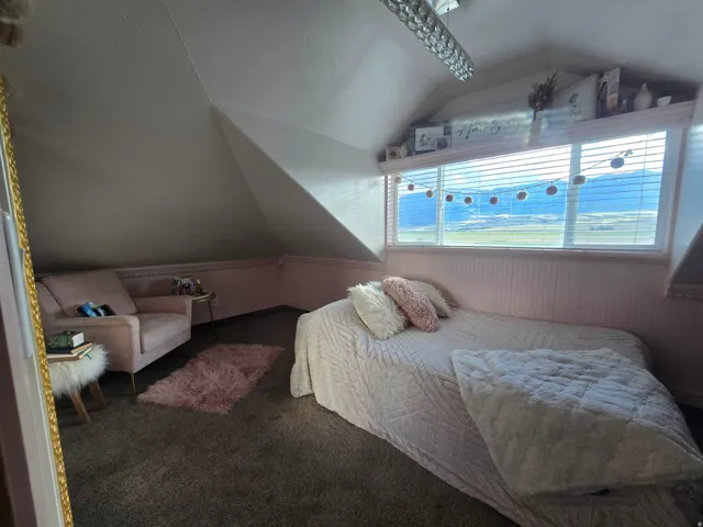 Attic room featuring sloped ceilings, a wide horizontal window with integrated blinds, and beadboard paneling