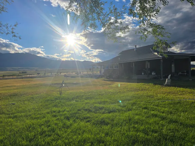 Expansive green lawn with a dark-sided ranch-style home featuring a covered porch and metal roof
