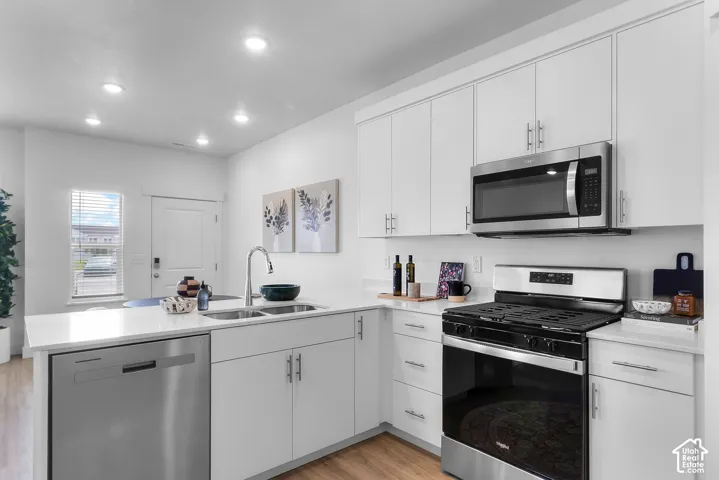 Modern kitchen featuring white cabinetry, light countertops, and wood-finish flooring