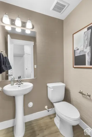 Pedestal sink with chrome faucet, complemented by wood-finish flooring