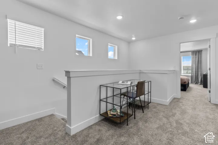 Carpeted upper level with white walls and trim, featuring three windows providing natural light