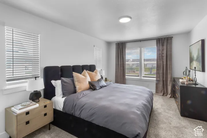 Carpeted room featuring a ceiling-mounted light fixture, multiple windows with blinds, and neutral-toned walls