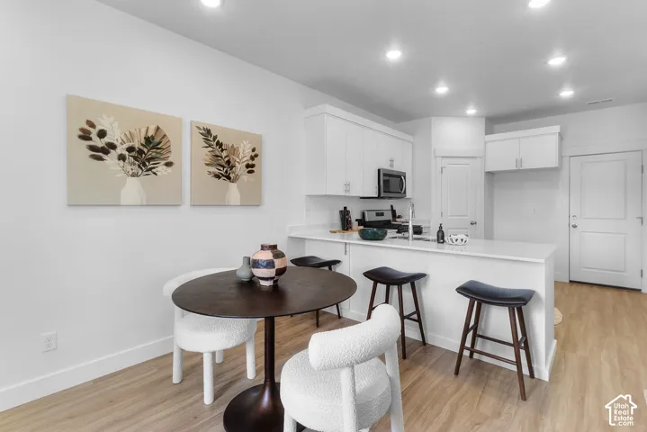 Kitchen featuring white shaker cabinetry, stainless steel microwave, and recessed lighting