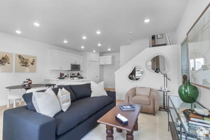 Open-concept living space featuring a modern kitchen with white cabinetry and stainless steel appliances, a dining area, and a living area with recessed lighting