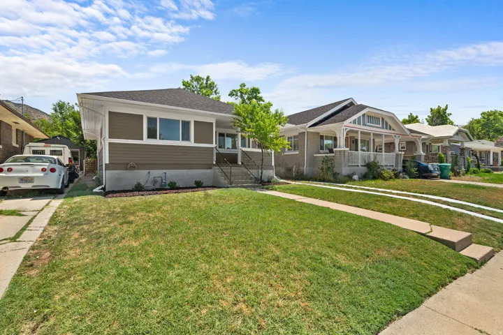 Siding exterior with white trim, a dark shingled roof, and a mature front lawn