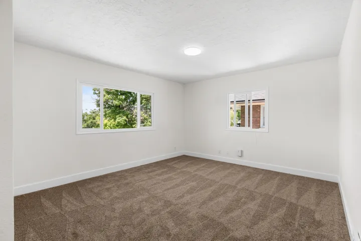 Spacious room featuring neutral carpeting, white walls, and bright white trim