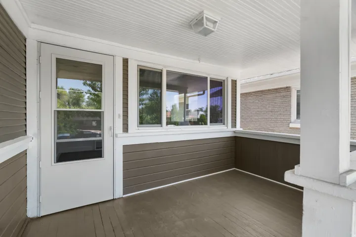 Enclosed porch featuring a white screen door, expansive windows, a tongue-and-groove ceiling, and wood-finish flooring