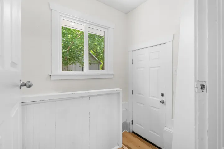 Entryway featuring a paneled door, wood-finish flooring, and a window with white trim