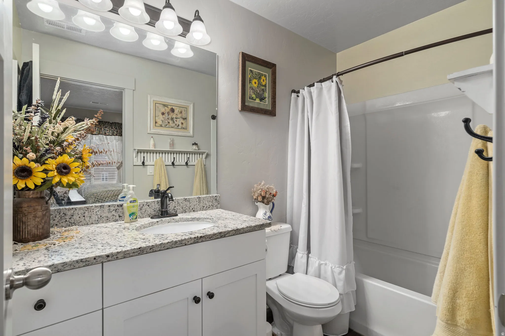 Bathroom featuring a white vanity with a speckled countertop, undermount sink, and dark-finish faucet