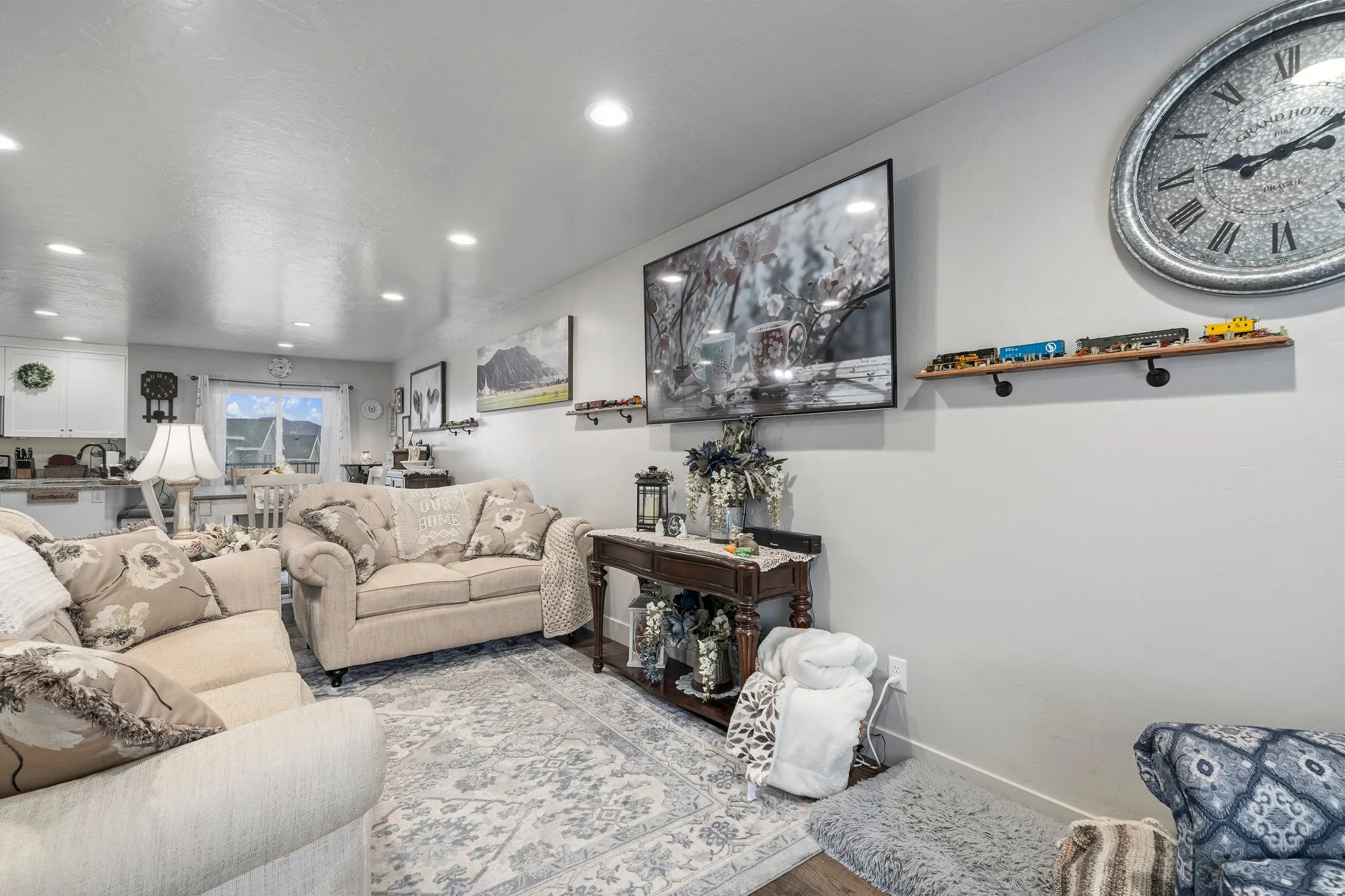 Recessed ceiling lighting illuminates the living area, featuring light-toned walls and wood-finish flooring