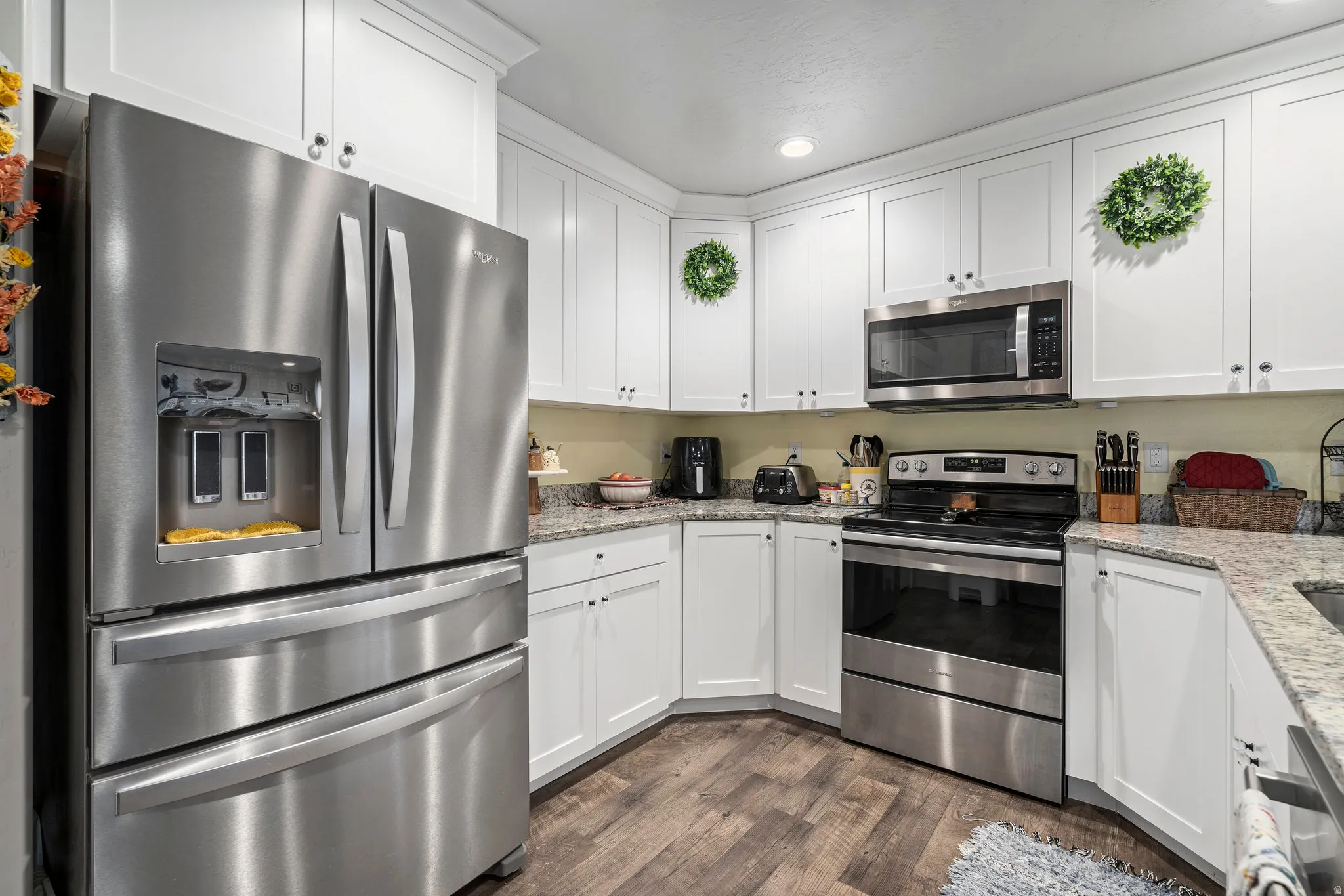 Modern kitchen featuring white cabinetry, stainless steel appliances, wood-finish flooring, recessed lighting, and light-toned countertops