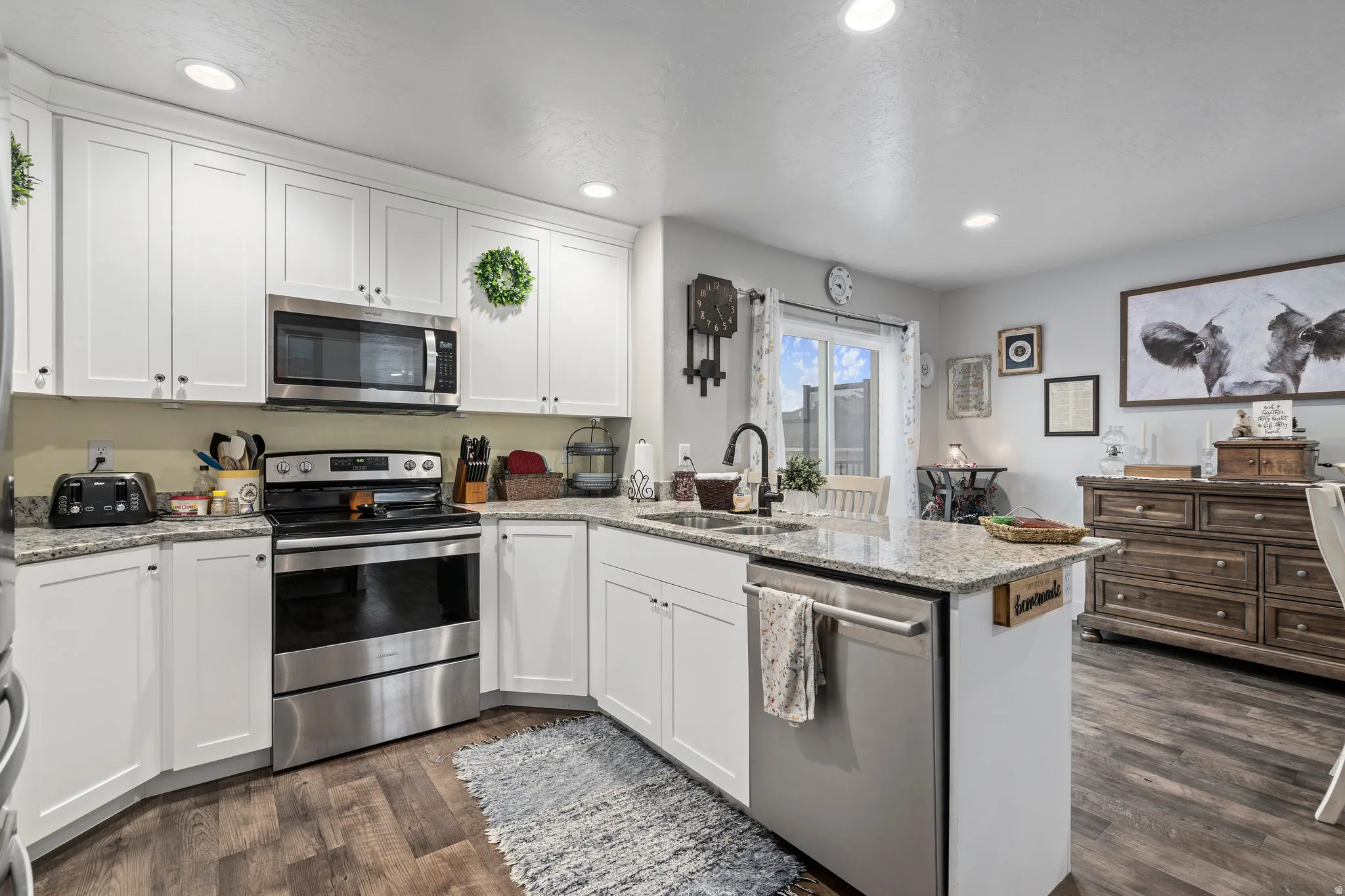 Kitchen featuring white cabinetry, stainless steel appliances, and granite-style countertops