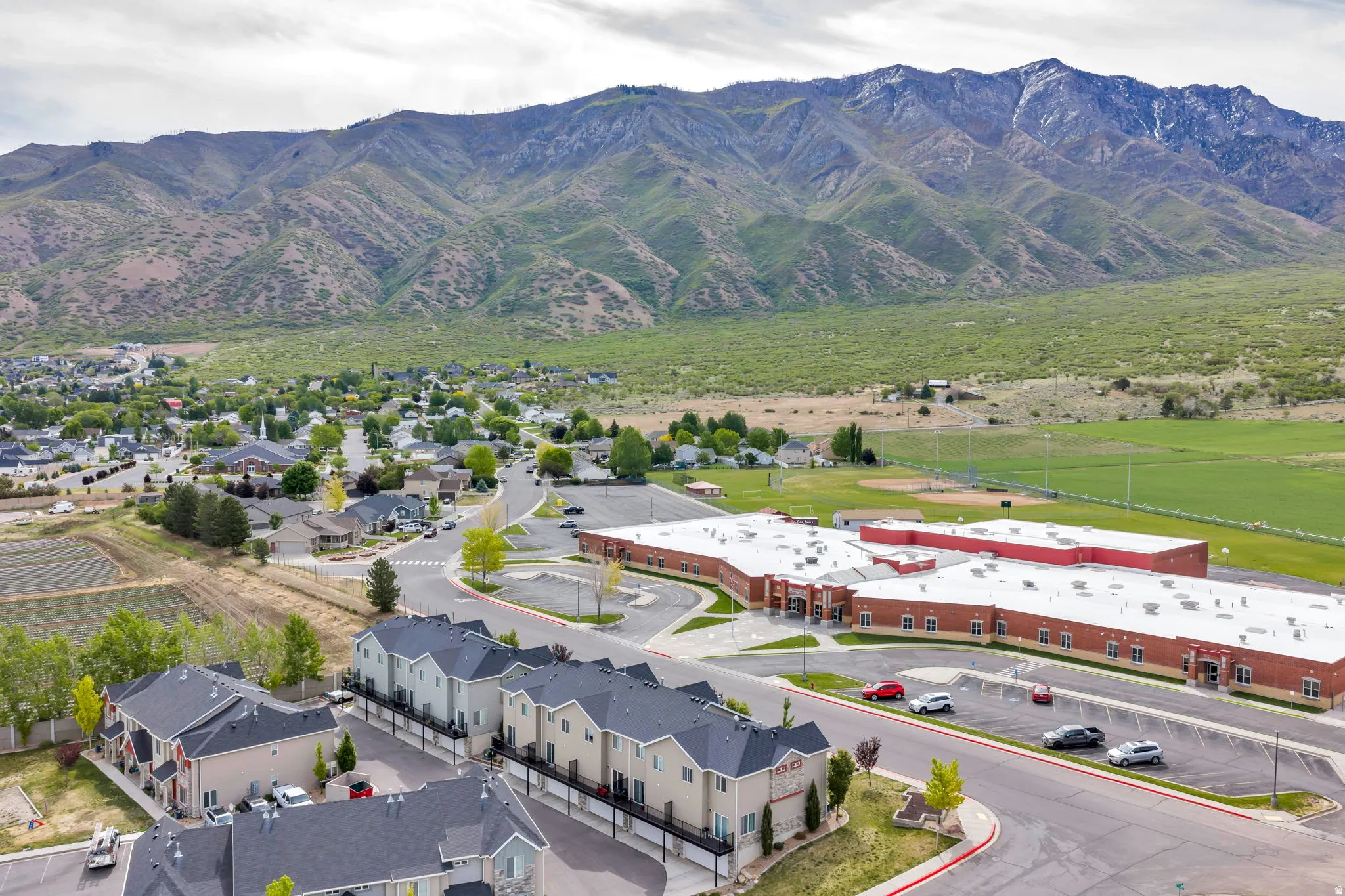 Aerial perspective showcasing mountainous terrain, green fields, and residential areas