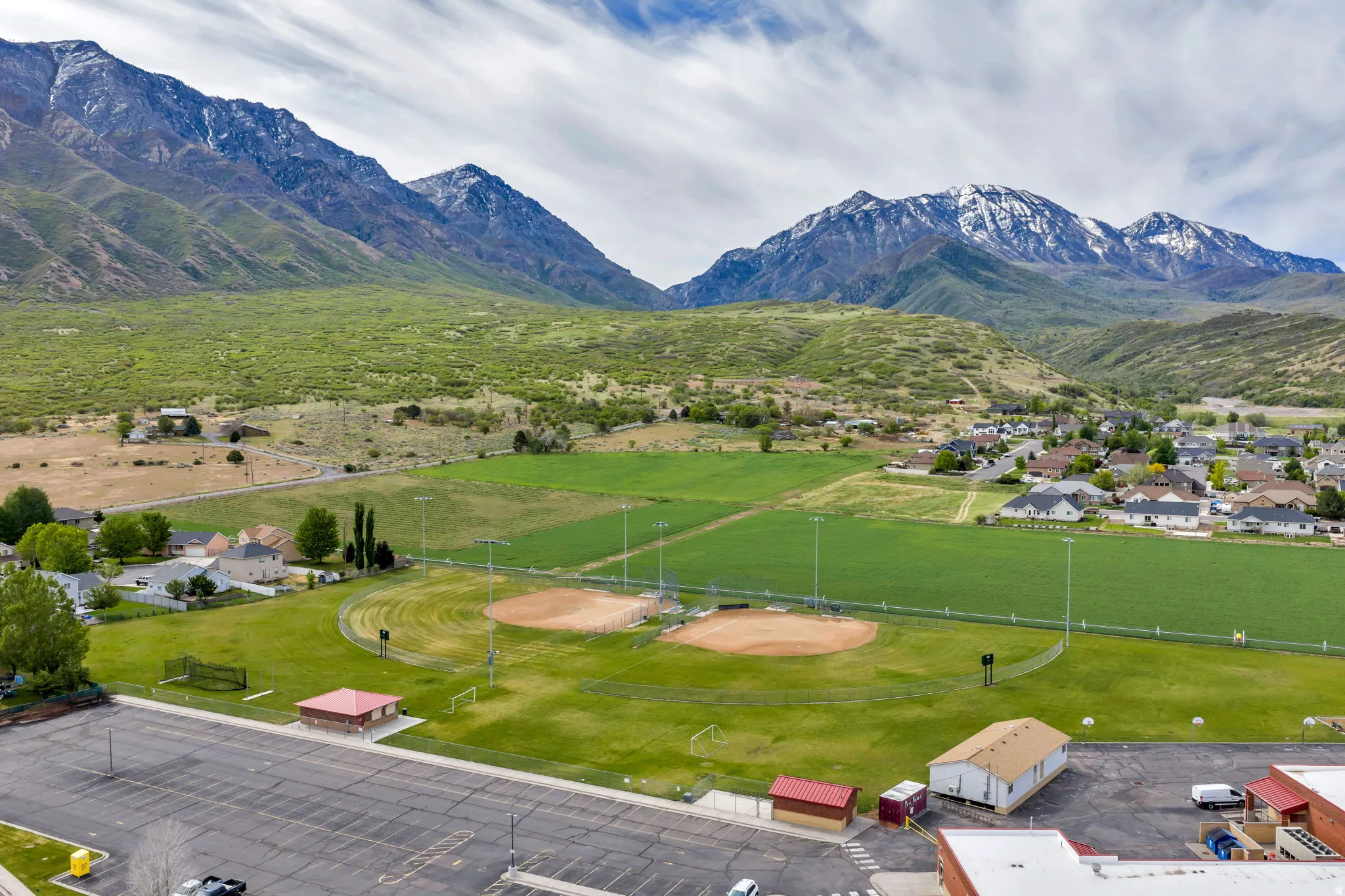 Expansive athletic fields featuring two baseball diamonds and green space, surrounded by residential areas and agricultural land