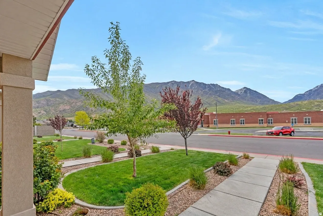 Front yard featuring a concrete walkway, manicured lawn, and planted landscape beds