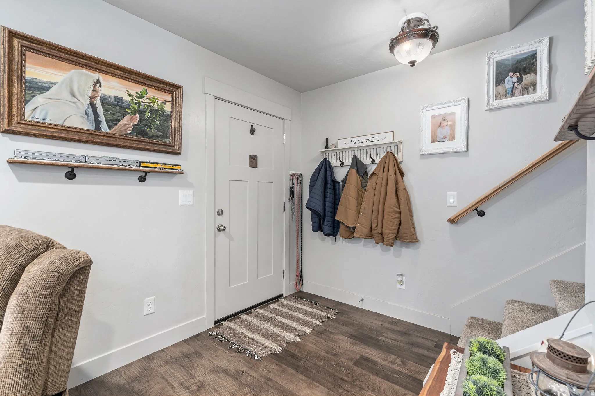 Inviting entry space featuring wood-finish flooring, a white paneled door, and a built-in coat rack