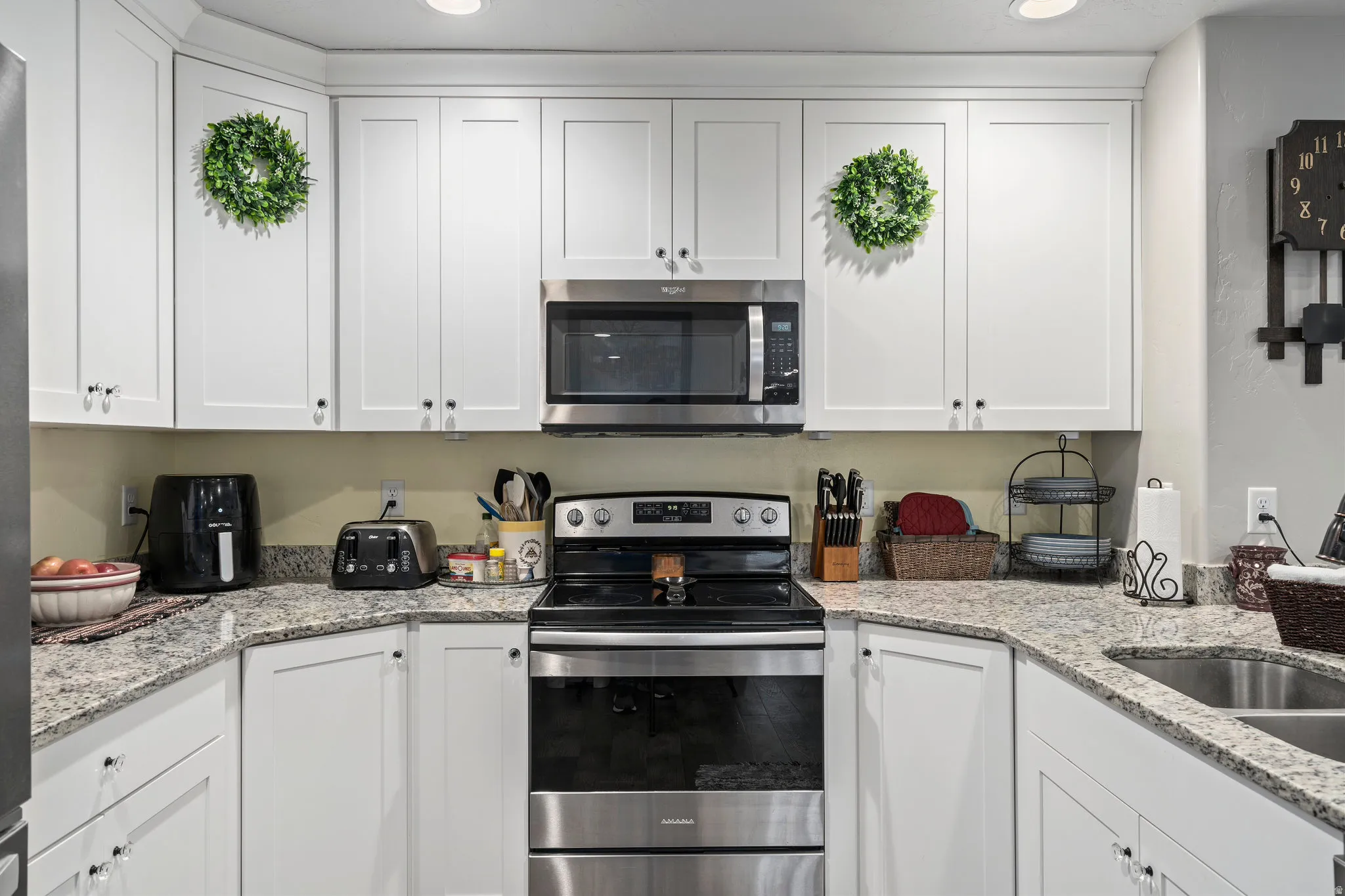 Kitchen featuring white shaker-style cabinetry, granite-finish countertops, stainless steel appliances, and recessed lighting