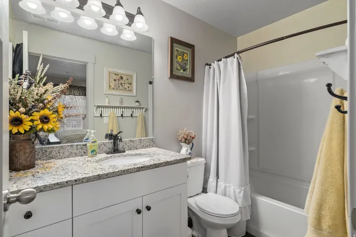 Bathroom featuring a white vanity with a speckled countertop, undermount sink, and dark-finish faucet