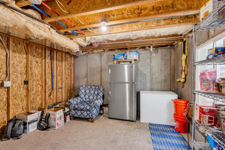 Unfinished basement space featuring exposed wood joists and subflooring, concrete foundation walls, and an insulated ceiling