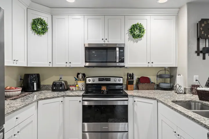 Kitchen featuring white shaker-style cabinetry, granite-finish countertops, stainless steel appliances, and recessed lighting