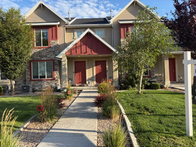 Two-story townhome featuring stone veneer and horizontal siding, red architectural accents, and dual red entry doors
