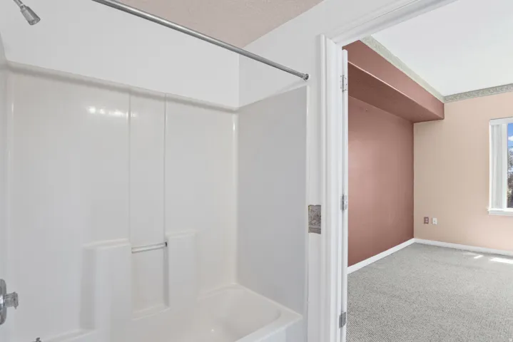 White fiberglass tub and shower combination with a curved shower rod