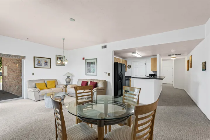 Open-concept living space featuring neutral carpeting and white walls