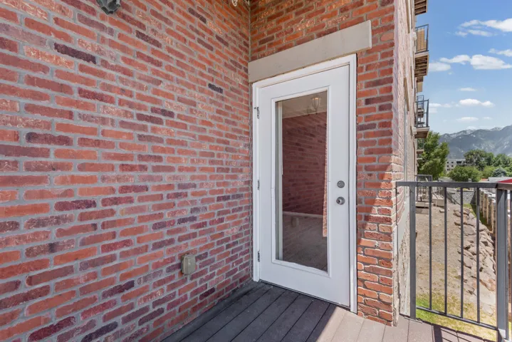 Outdoor balcony featuring a white glass-paneled door, composite decking, and a black metal railing