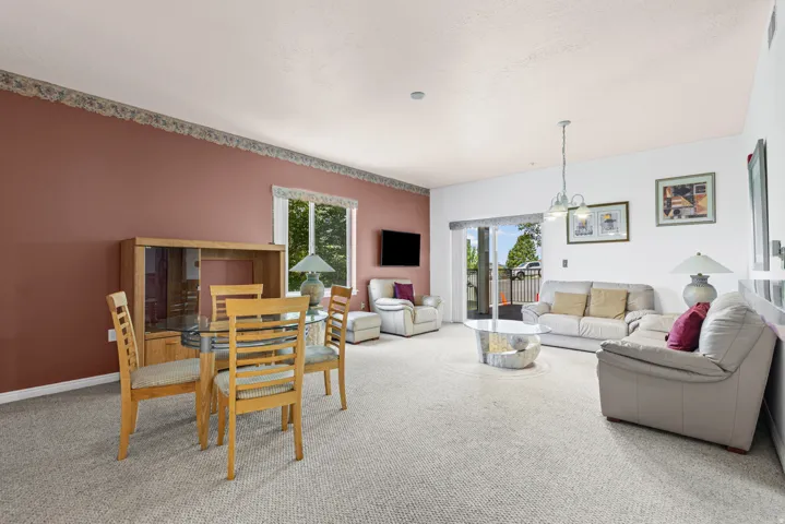 Open-concept living area with neutral carpeting and a sliding glass door