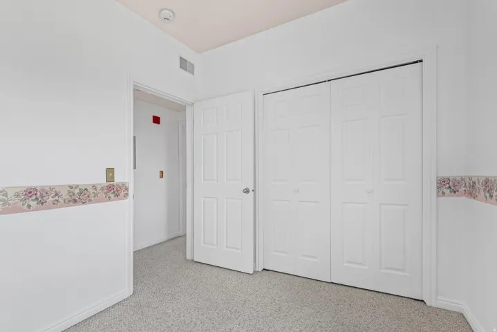 Carpeted interior space featuring white walls with floral wallpaper border and white trim