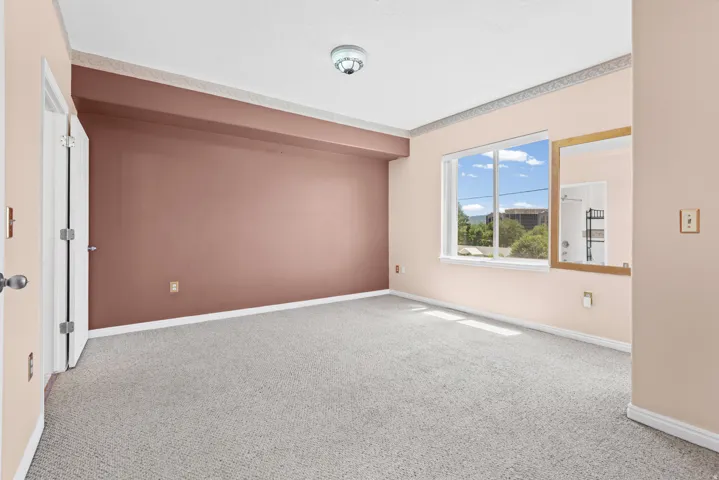 Carpeted room featuring a large window, light-colored walls, and a contrasting accent wall