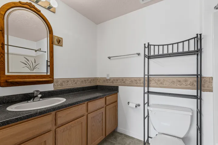 Bathroom vanity with wood-finish cabinetry, integrated sink, and dark speckled countertop