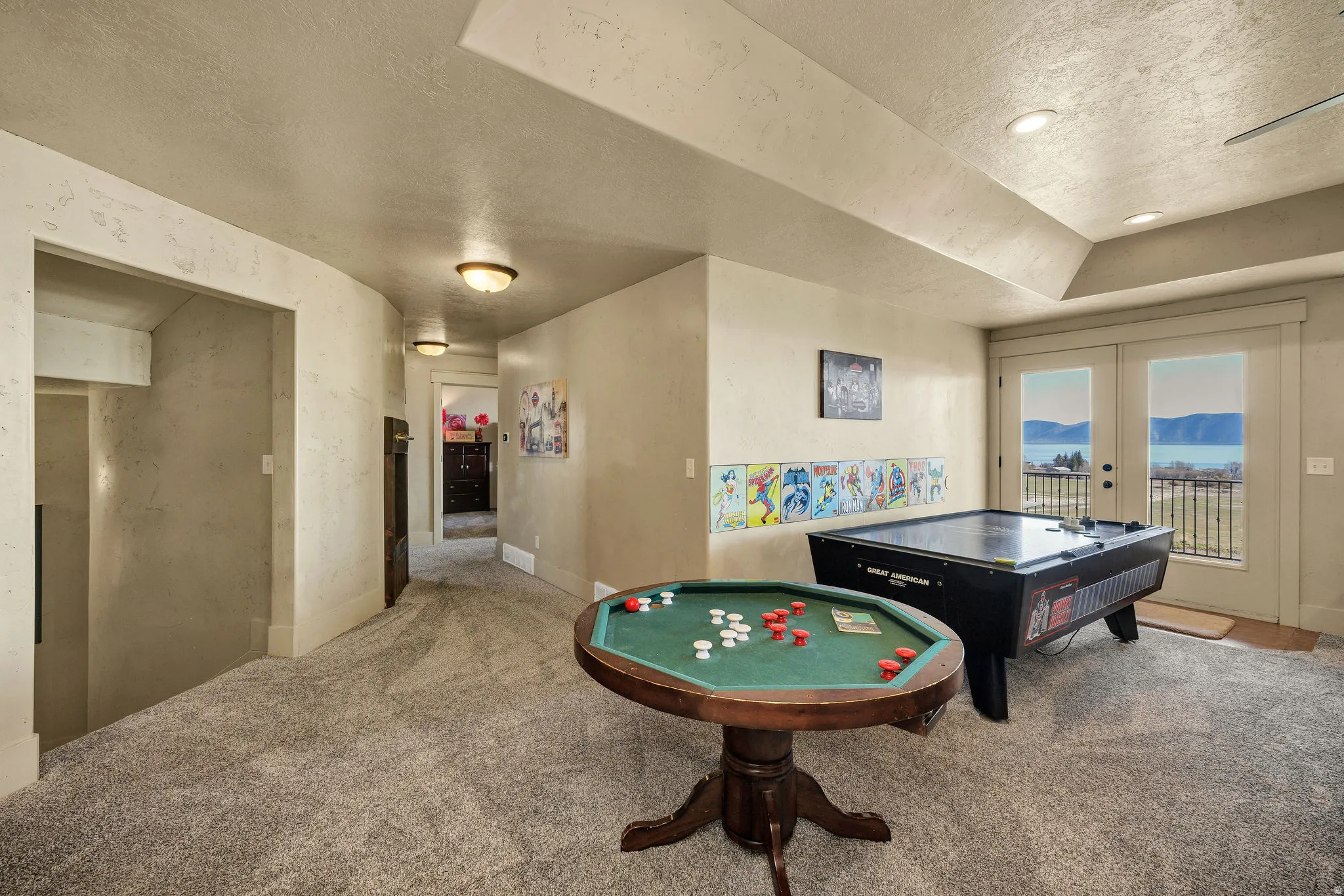 Recreational room featuring plush grey carpet, recessed lighting, and french doors opening to a wrought iron balcony
