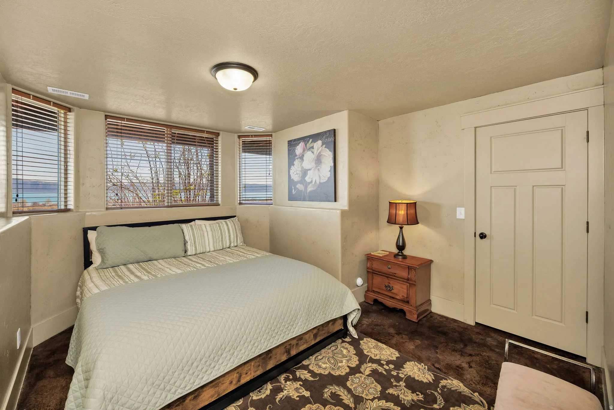 Room featuring multiple windows with horizontal blinds, offering exterior water views