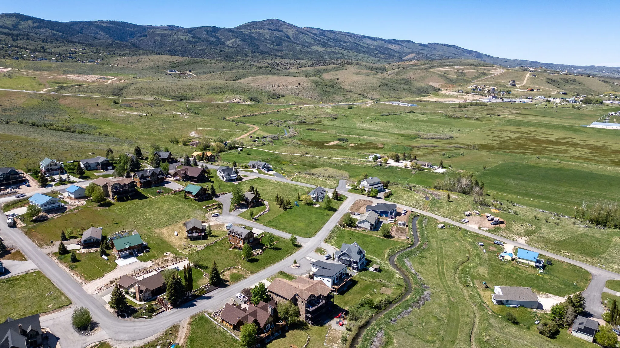 Expansive landscape featuring scattered residential properties, paved roadways, and a natural water feature