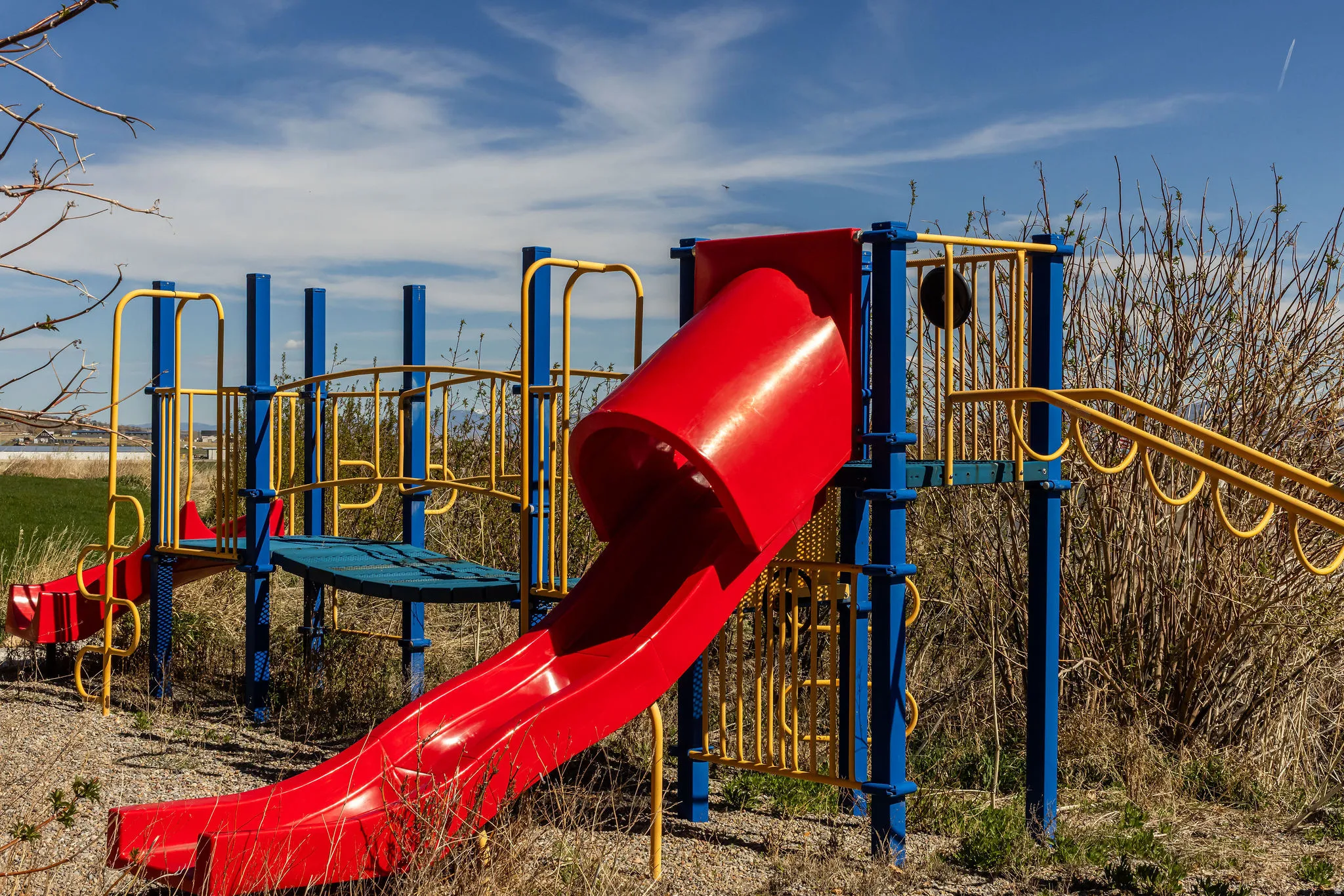 Outdoor playset featuring a red slide, blue support beams, and yellow railings