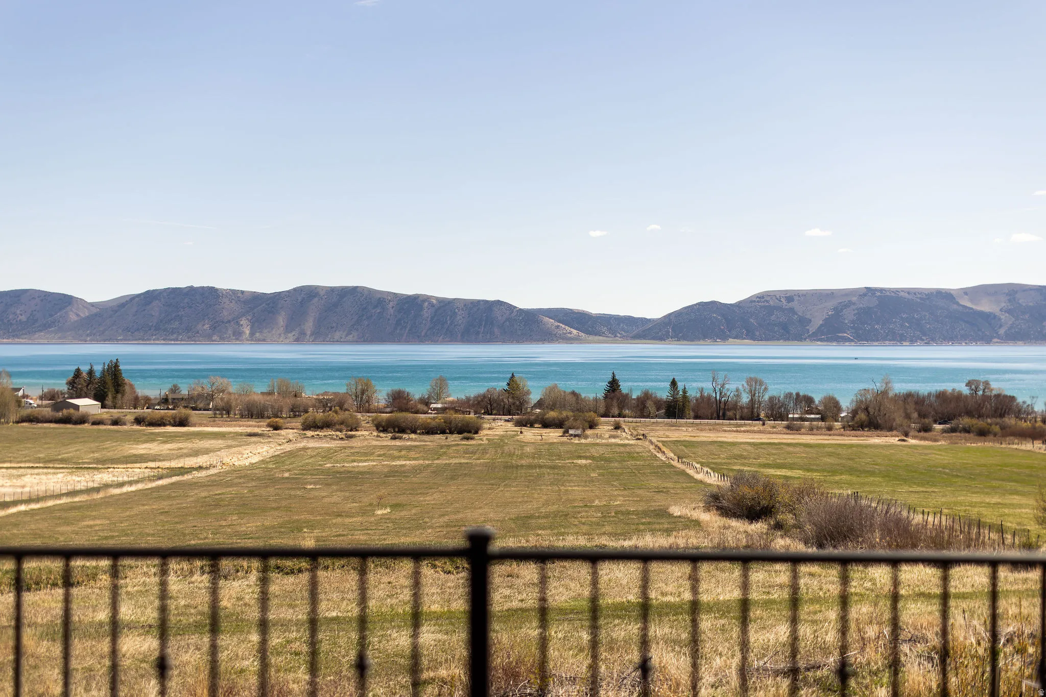 Expansive landscape featuring a freshwater lake, surrounding mountains, and verdant fields