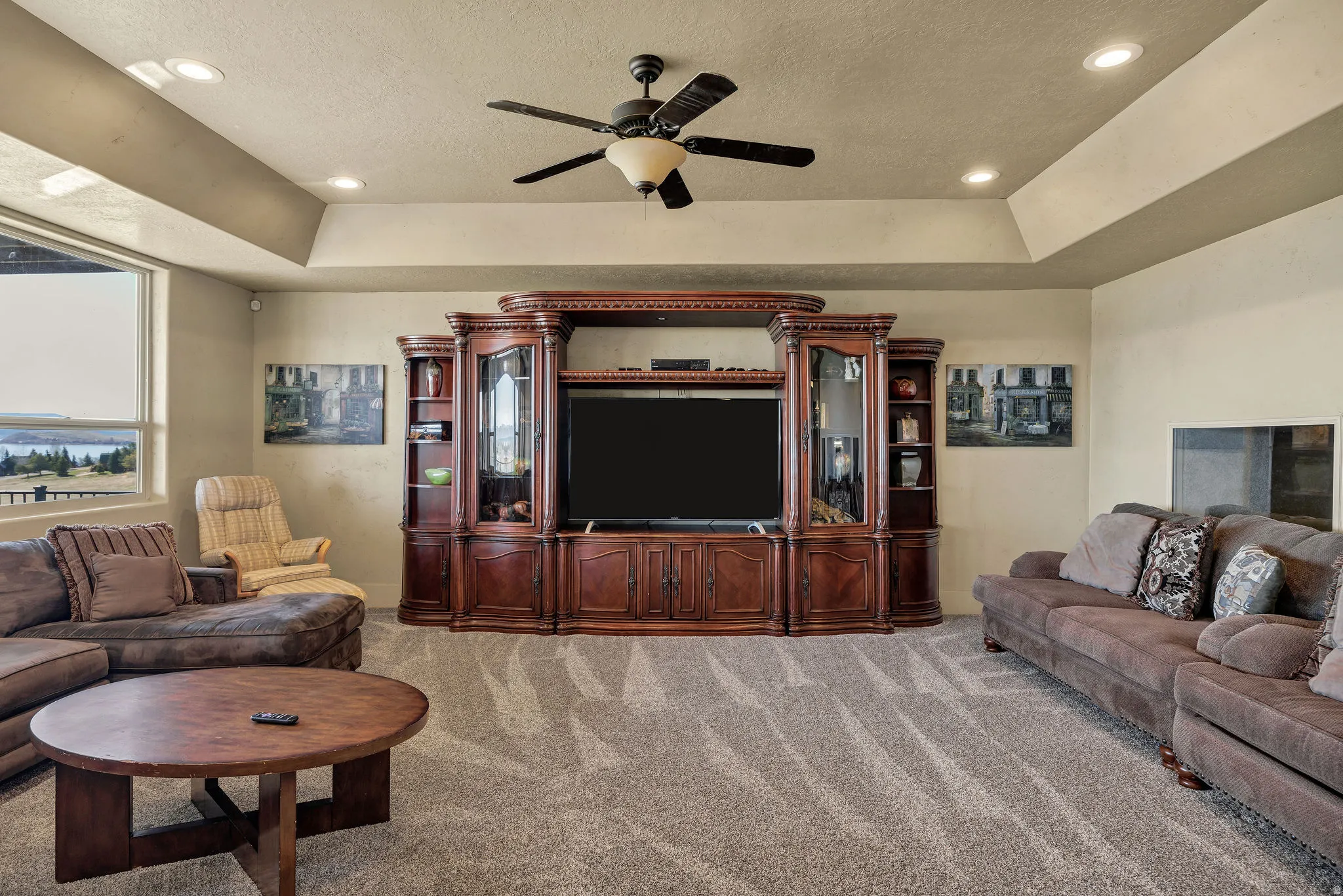 Spacious living area featuring a large built-in entertainment center with glass-front cabinets and ornate wood detailing