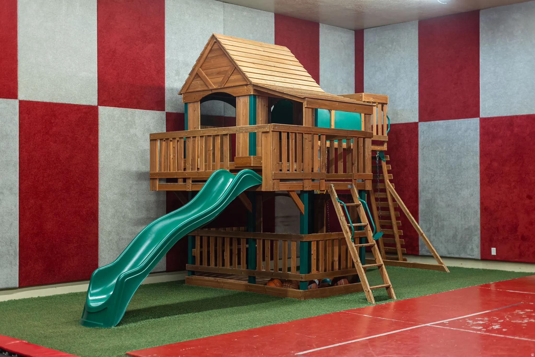 Indoor play structure featuring multiple levels, an integrated slide, and two ladder entry points