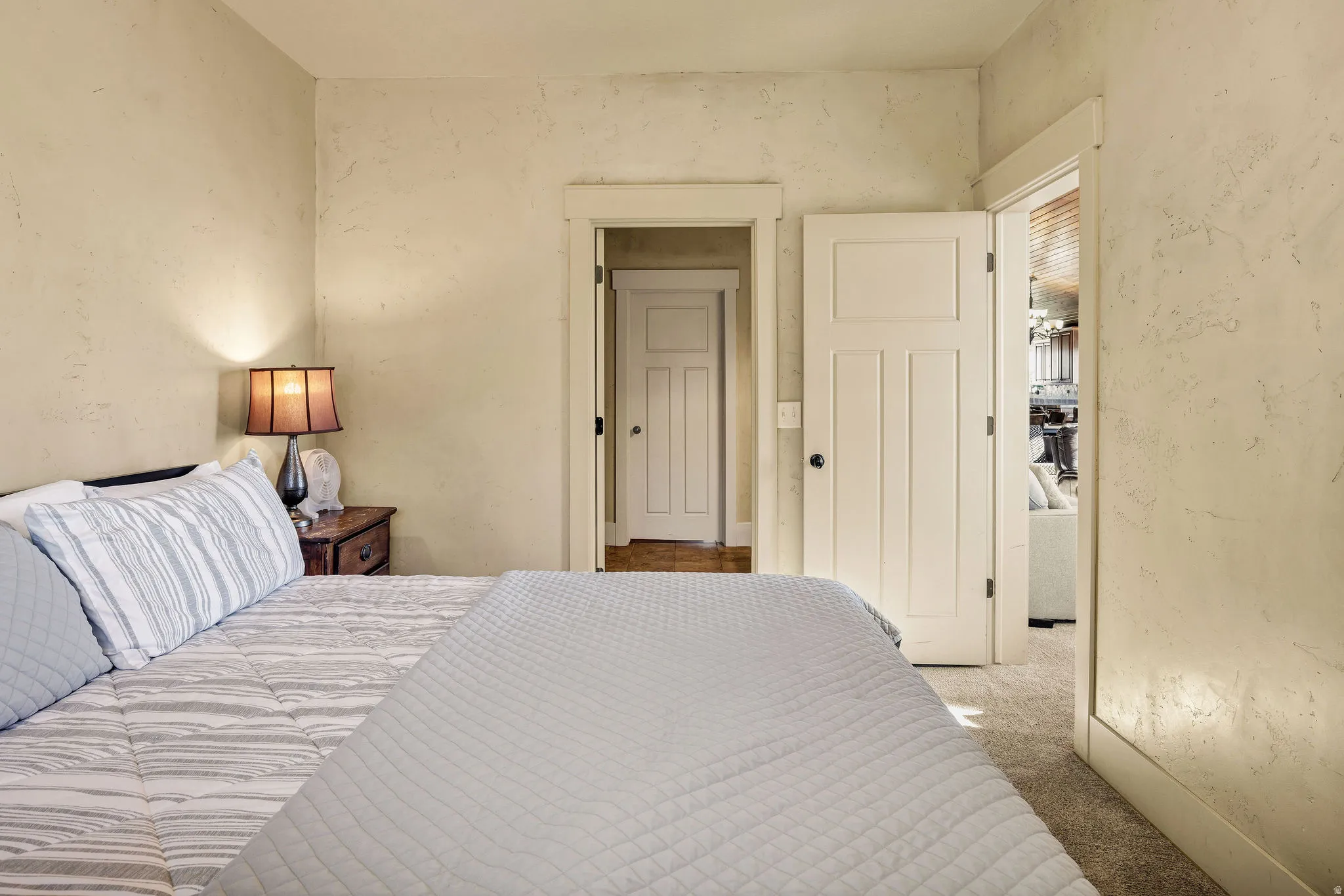Bedroom featuring textured walls, carpet flooring, and a solid-core interior door with panel detailing