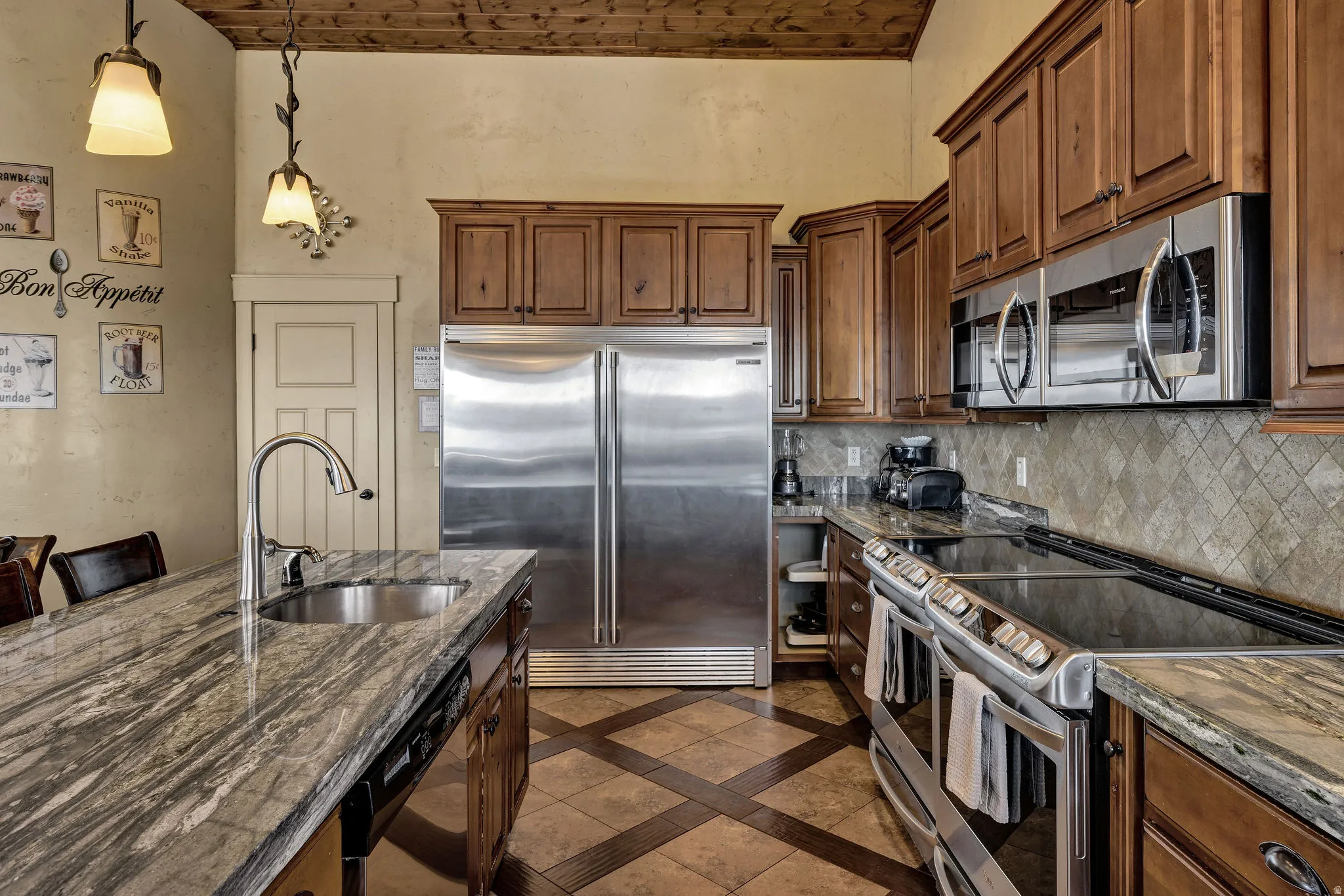 Gourmet kitchen featuring a substantial island with an undermount sink and gooseneck faucet, stainless steel appliances, rich wood cabinetry, and a patterned tile backsplash