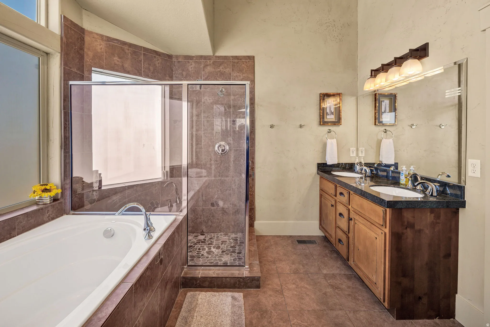 Bathroom featuring a built-in tub, tiled shower with glass enclosure, and a double vanity with an integrated countertop