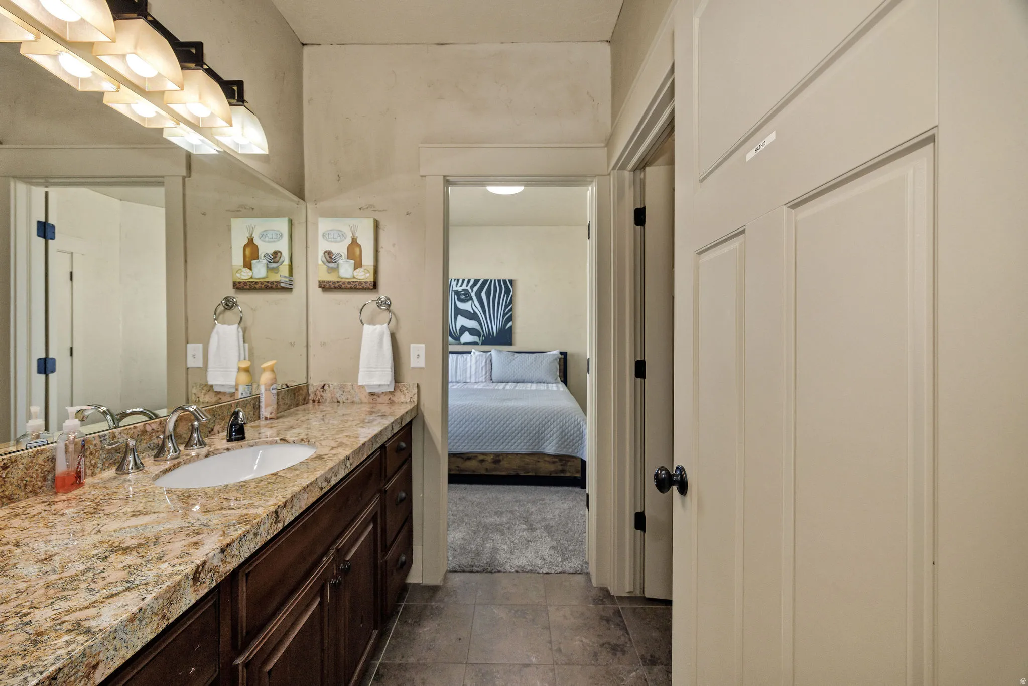 Bathroom vanity featuring a polished stone countertop, undermount sink, and dark wood cabinetry