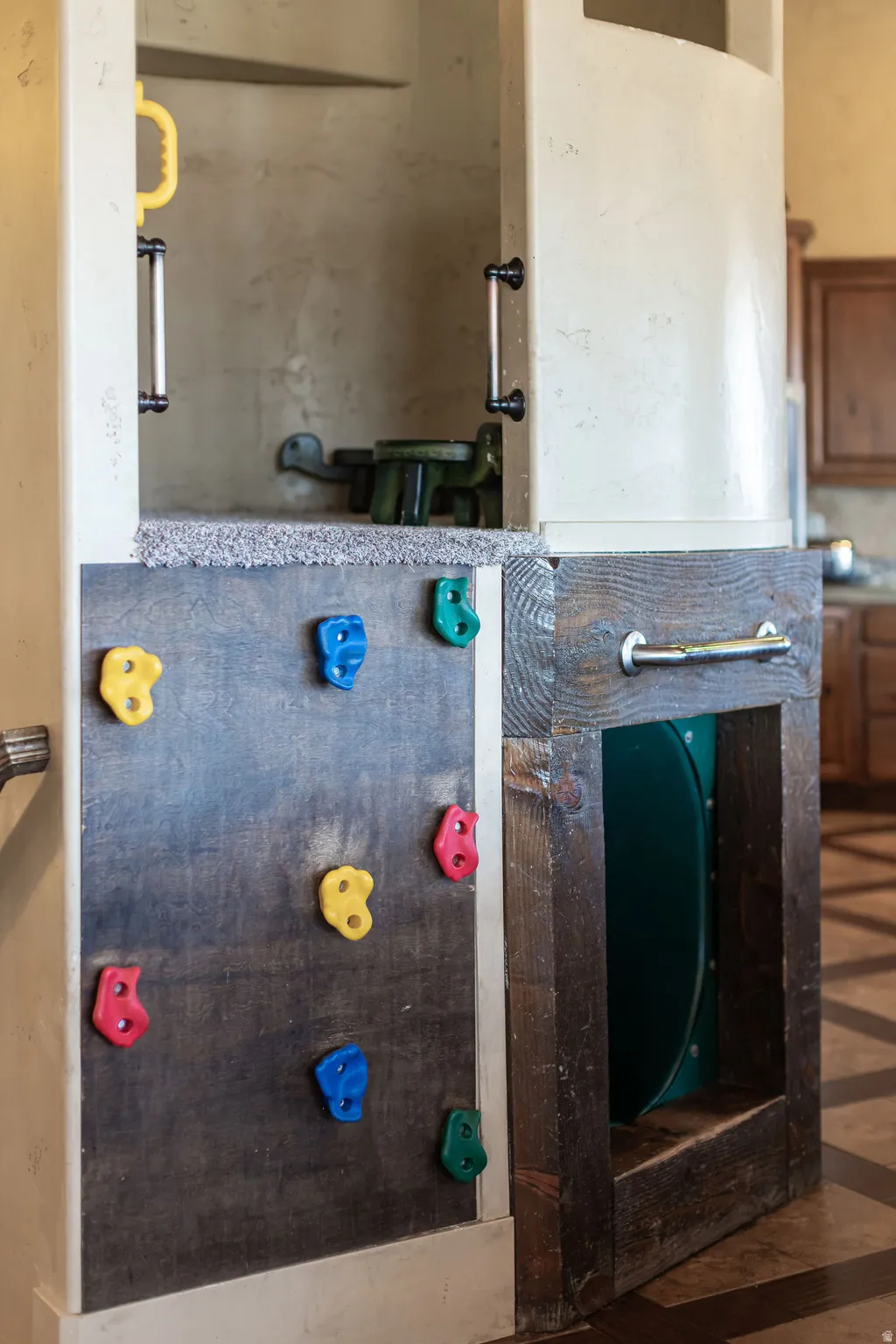 Built-in play structure featuring a climbing wall with colorful holds, a carpeted platform, and a slide entry