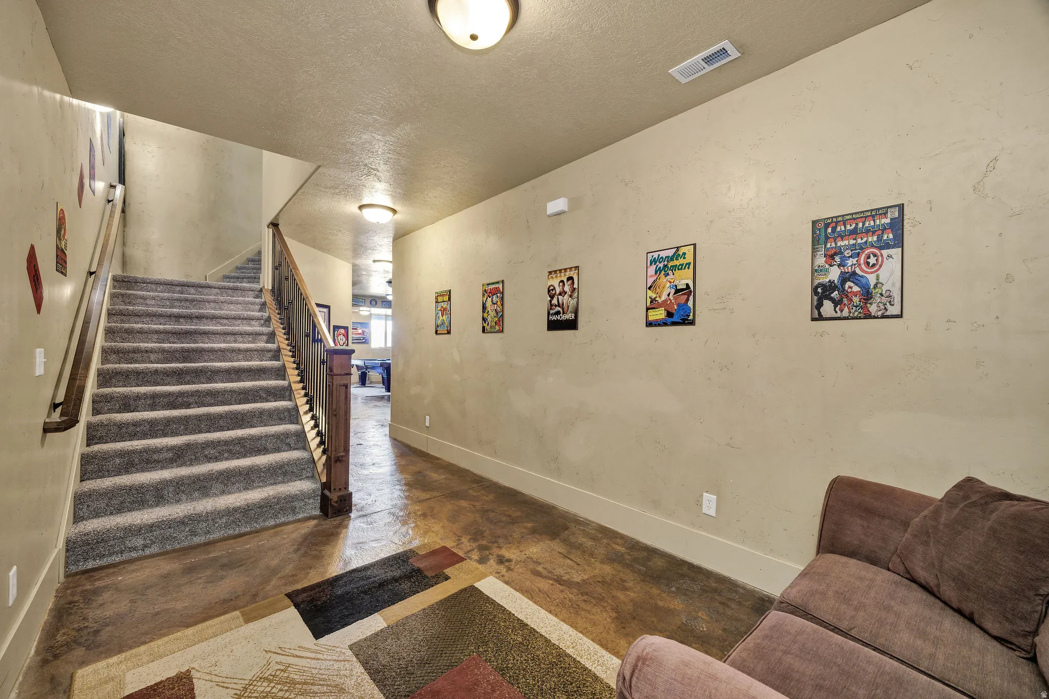Staircase featuring carpeted treads and wood handrails with metal spindles, stained concrete flooring, and recessed ceiling lighting